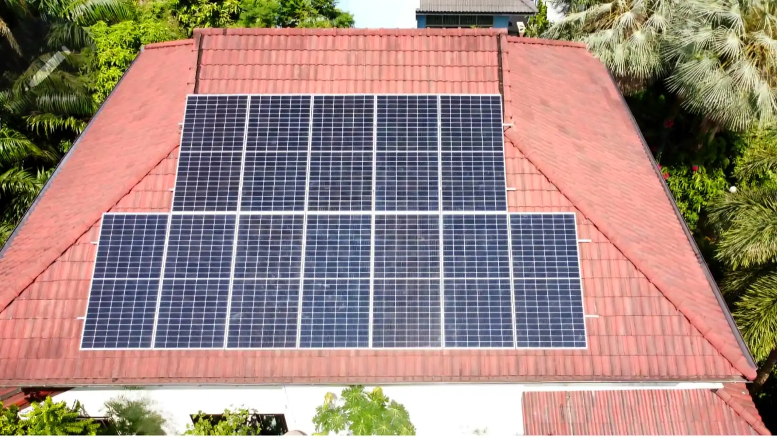 Rooftop solar panel array installed on a residential property in tropical surroundings